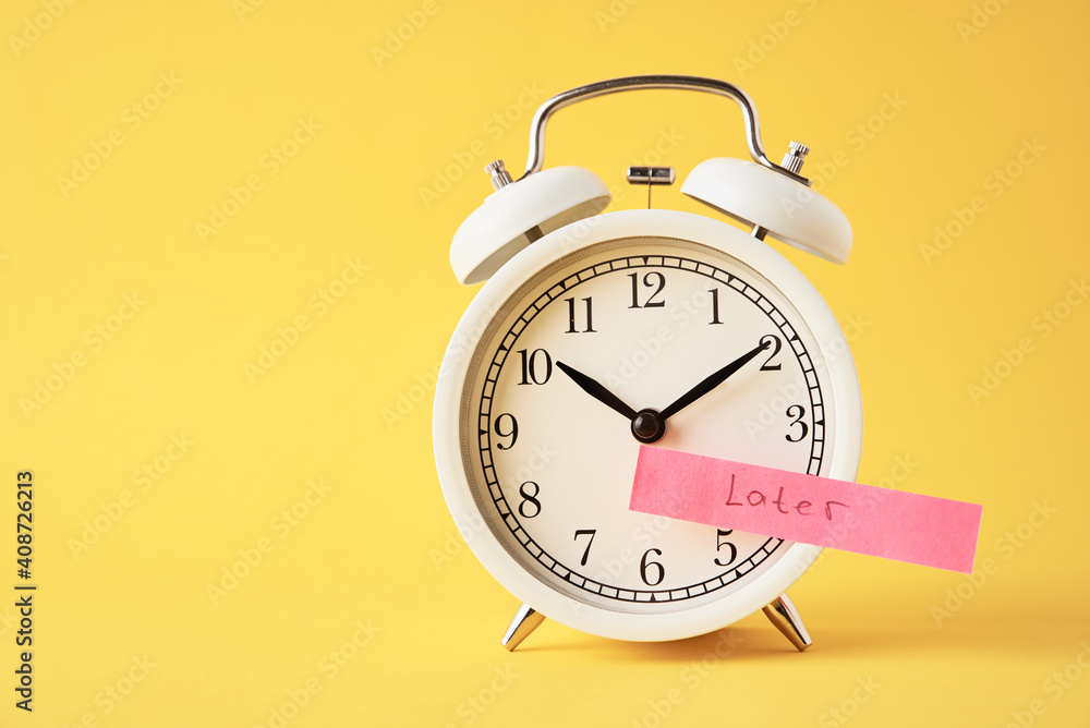 Procrastination and delay concept. Sticky note with word later on white alarm clock on yellow background. Urgency time Procrastination and delay concept. Sticky note with word later on white alarm clock on yellow background. Urgency time