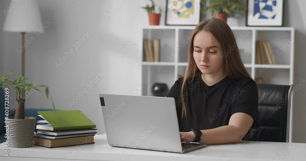 serious woman dressed black t-shirt is working with laptop in home office, typing in online chat in social nets, smm or seo specialist serious woman dressed black t-shirt is working with laptop in home office, typing in online chat in social nets, smm or seo specialist