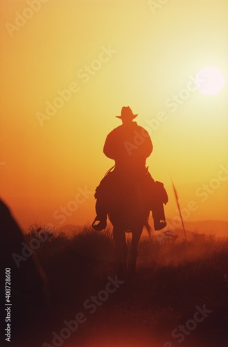 Silhouette of a cowboy riding horse at sunset, Texas, USA photo