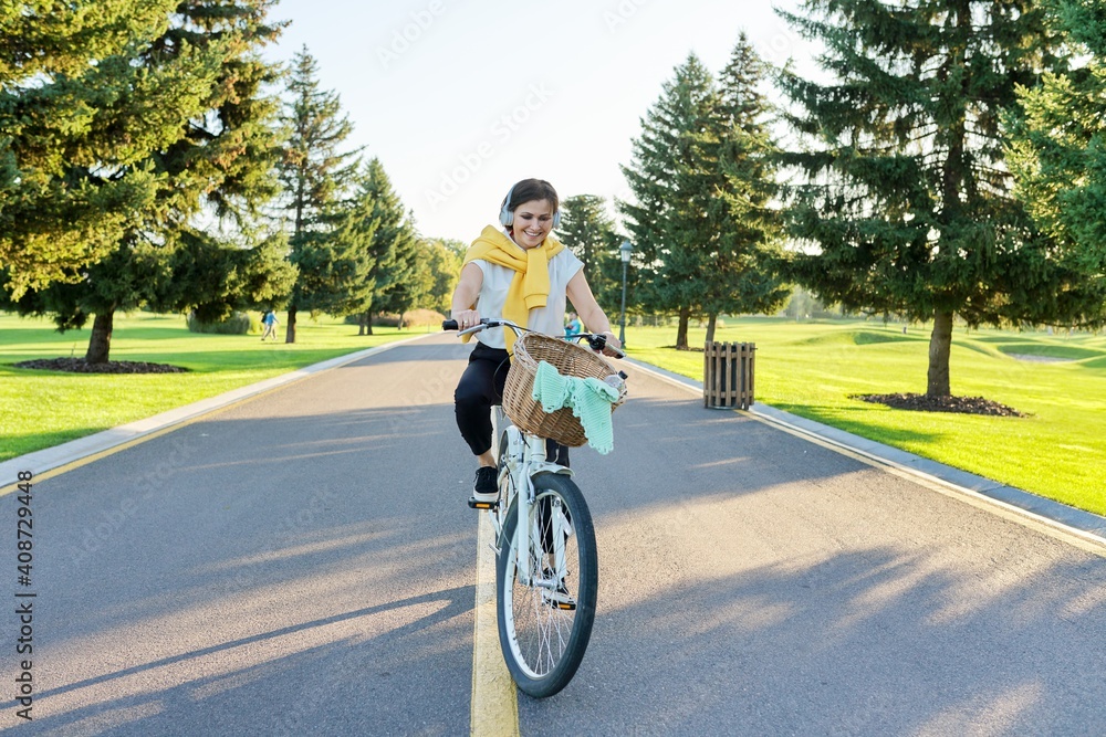 Beautiful active mature woman with bike on the road in the park Beautiful active mature woman with bike on the road in the park