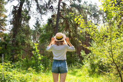 Hipster girl in straw hat standing in the forest. Wanderlust concept. Travelling ideas. Beautiful woman in the nature. Summer vibes.  Psychology. © Vadym
