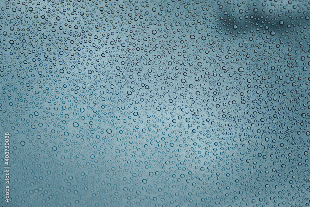 Close up of rain drops on a car glass in a cloudy day from the interior of the car