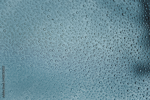 Close up of rain drops on a car glass in a cloudy day from the interior of the car
