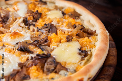 Pizza with cheese and mushrooms on a wooden plate. Close-up, selective focus