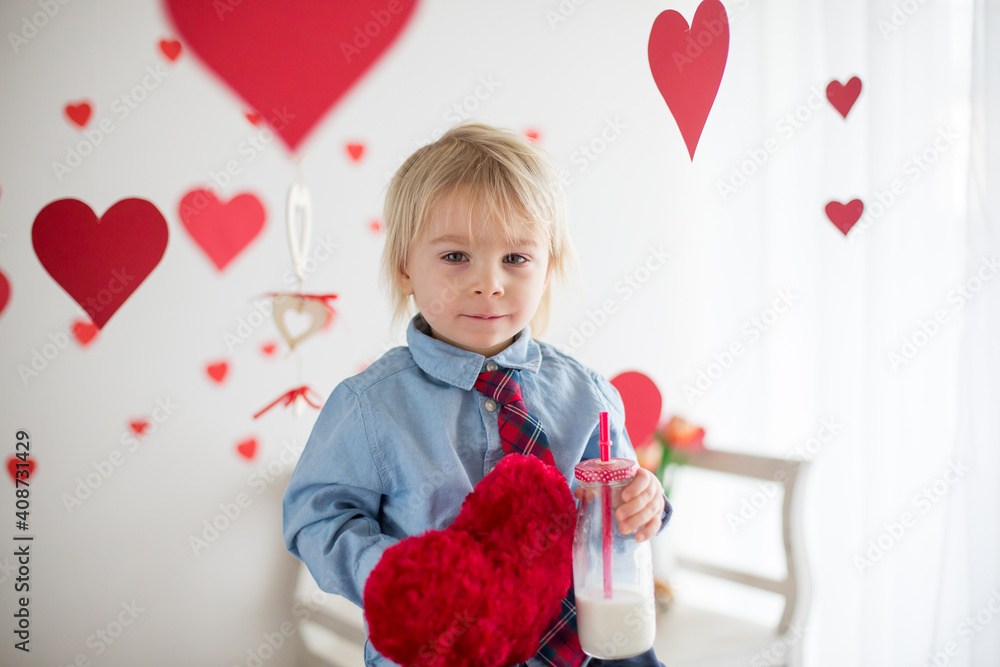 Cute blonde toddler boy, holding heart toy and playing with hearts for Valentine Cute blonde toddler boy, holding heart toy and playing with hearts for Valentine