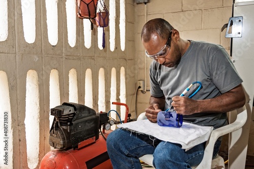 Ecuador, Galapagos Islands, Man etching design into glass cup in artisan workshop