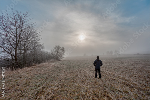 man silhouette walk into the misty foggy countryside in dramatic mystic sunrise scene