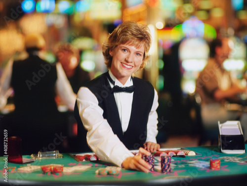 Female casino worker placing gambling chips on a table photo