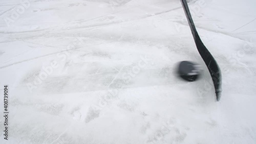 Hockey stick and puck on ice top view. Puck possession. Dribbling. Ice hockey. Outdoor ice hockey on the river ice. Close up