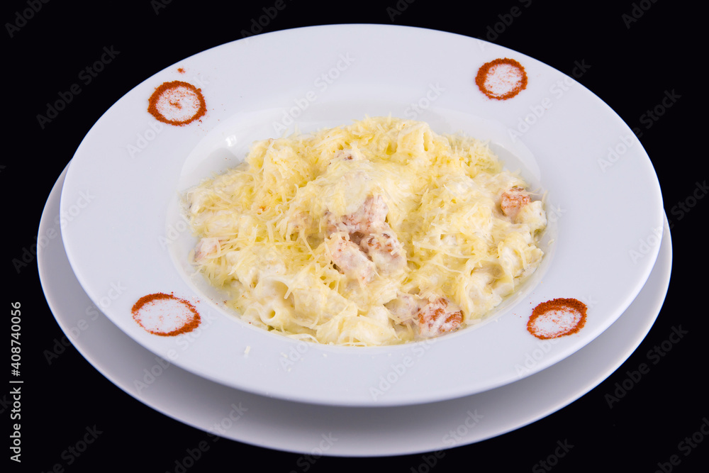 Fettuccine with salmon in cream sauce on white plate on black background Fettuccine with salmon in cream sauce on white plate on black background