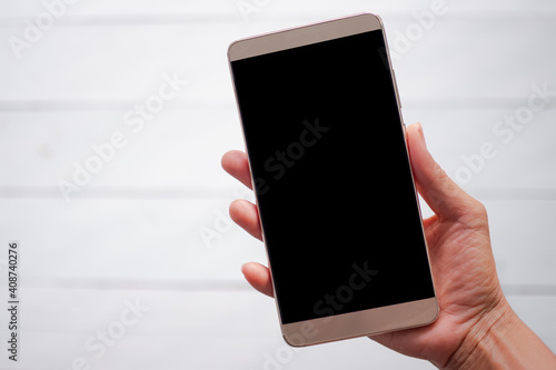 Hand holding a mobile phone on wooden background blured. copy space for add text or presentation. blank smart phone. social media online network thecnology for business concept. photo