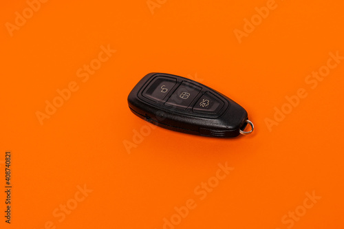 Modern car remote key on the orange isolated background