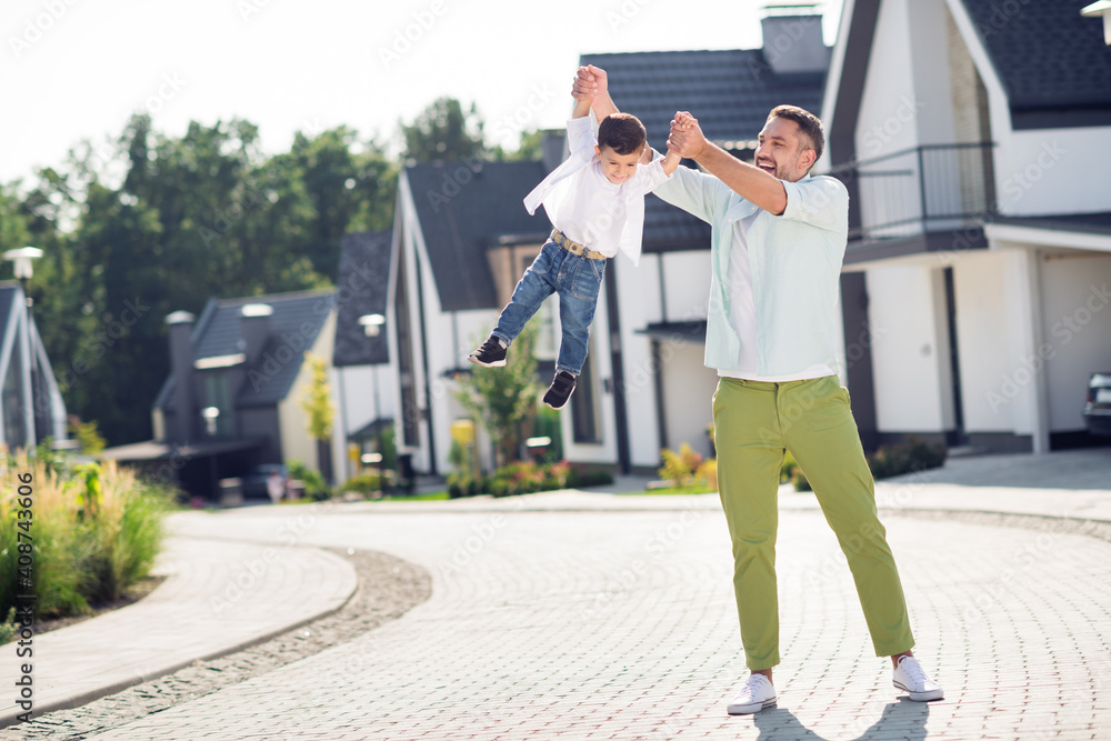 Full length body size view of attractive cheerful funky friends daddy carrying son having fun outside sunny summer day calm street Full length body size view of attractive cheerful funky friends daddy carrying son having fun outside sunny summer day calm street