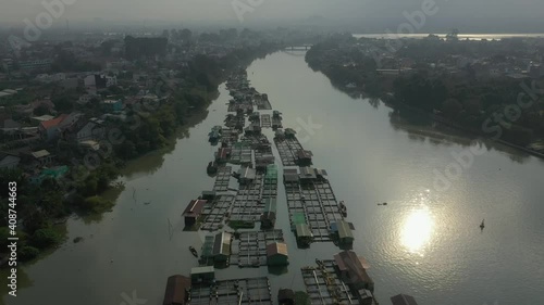 Floating fish farming community in Bien Hoa on the Dong Nai river, Vietnam on a sunny day. Drone flying along river. photo