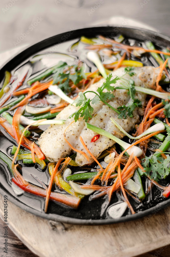 chinese style steamed fish fillet with vegetables on hot plate