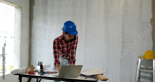 Young engineer asian woman construction engineer in construction site. Concept Architect and desk of Architectural project in construction site or office building with wearing safety equipment.