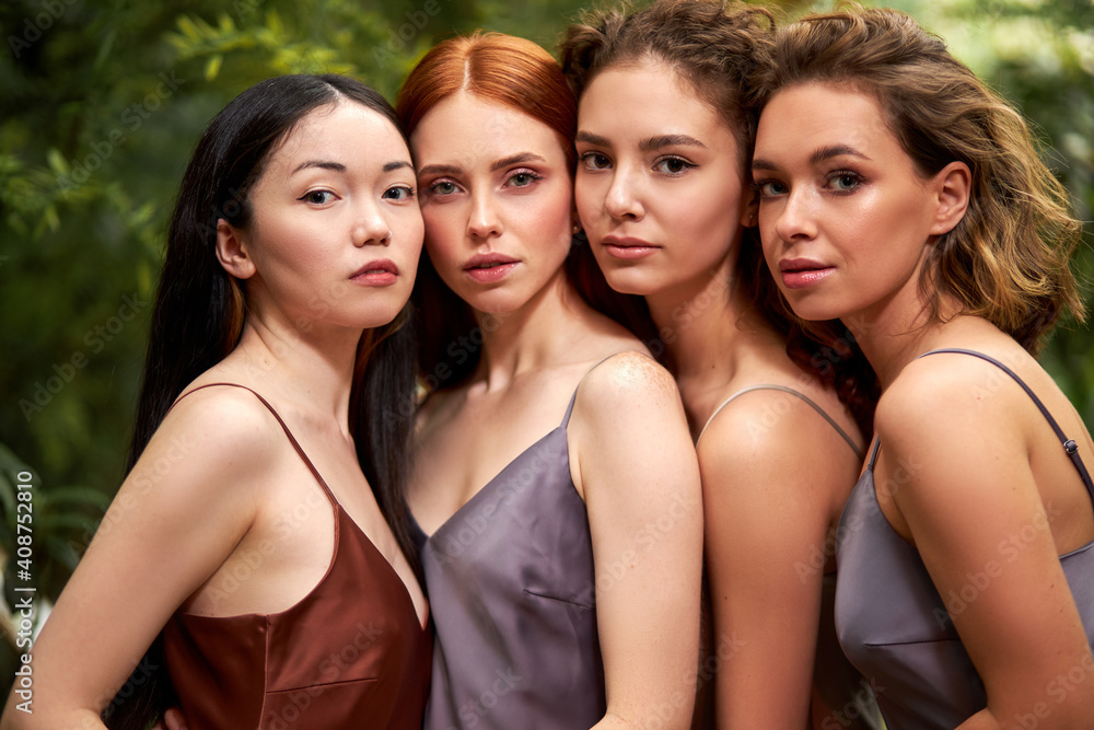 four diverse ladies in elegant dresses posing in nature green garden. natural beauty concept. women stand leaning on each other four diverse ladies in elegant dresses posing in nature green garden. natural beauty concept. women stand leaning on each other