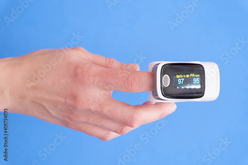 Oximeter on finger on blue background