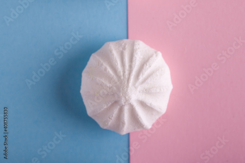 White sweet meringue on pastel blue and pink background. Top view.