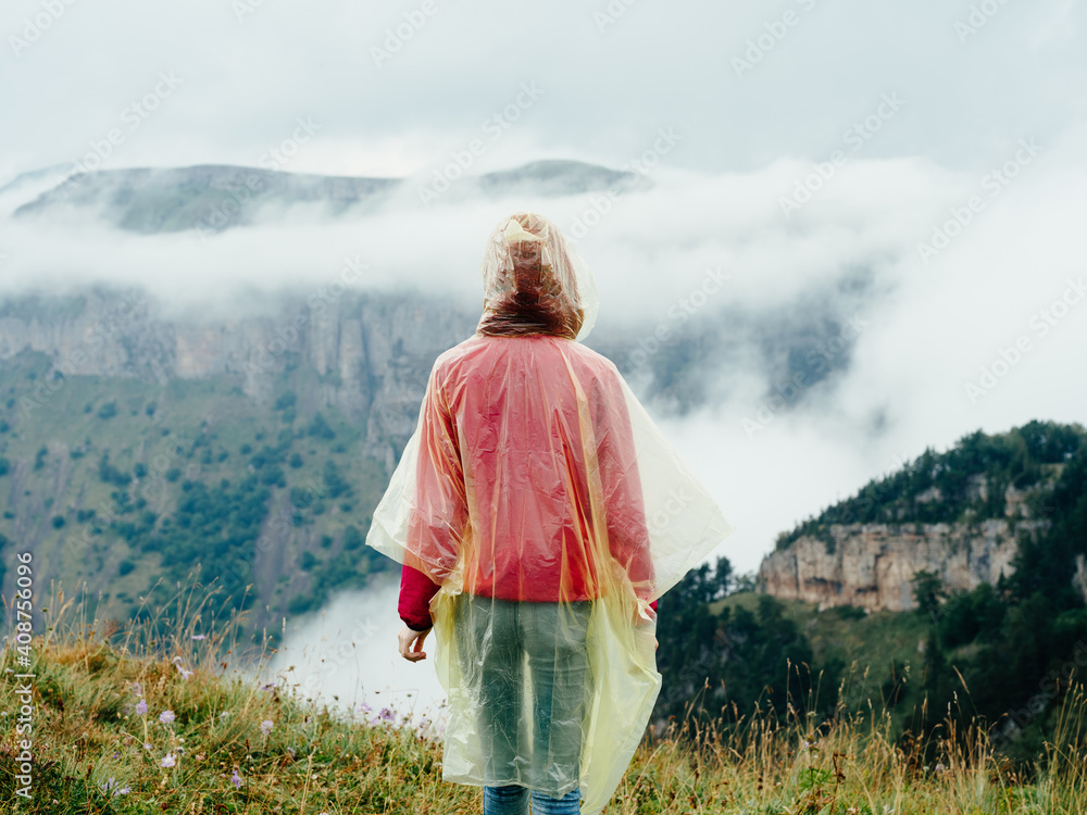 Woman in the mountains with a cape on her shoulders and mountains fresh air fog nature