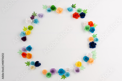 On a white background with space for writing text, multicolored paper flowers are placed in a circle.