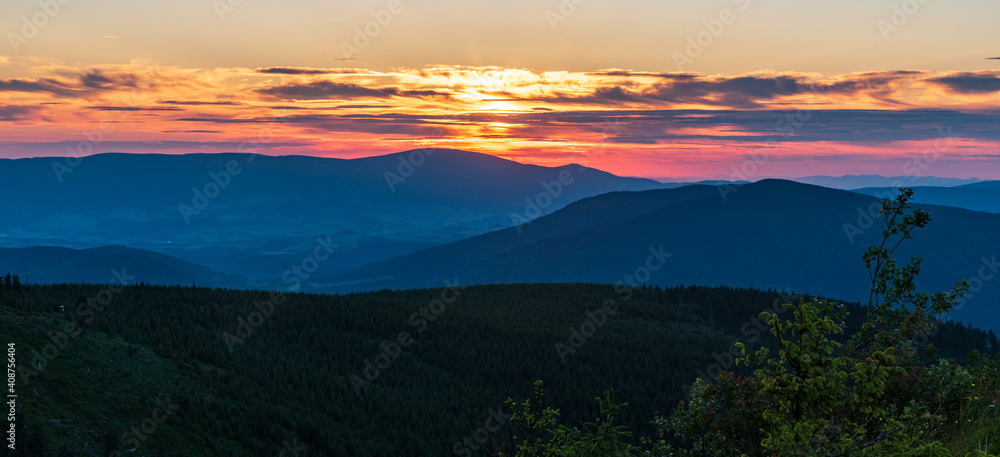 Sunset with hills, colorful sky and clouds from Dlouhe strane hill in Jeseniky mountains in Czech republic