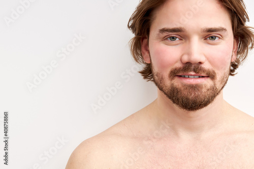 smiling shirtless man having bristle looking at camera, young caucasian male model isolated over white background