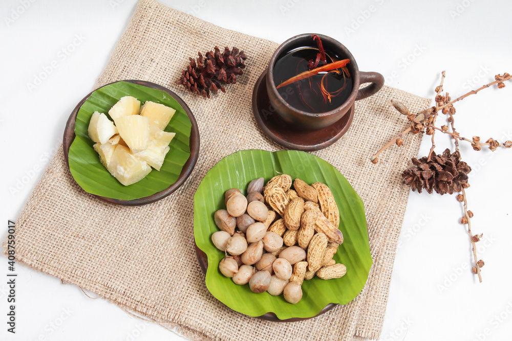 Bogor beans (Vigna subterranea), peanuts (Arachis hypogaea L.) and cassava are served on a woven plate and banana leaves on a white background. isolated Bogor beans (Vigna subterranea), peanuts (Arachis hypogaea L.) and cassava are served on a woven plate and banana leaves on a white background. isolated
