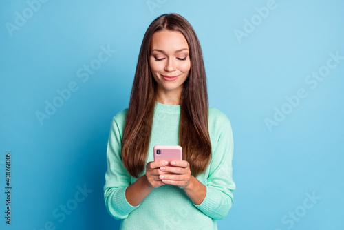 Portrait of attractive focused cheery brown-haired girl using device gadget browsing isolated over bright blue color background