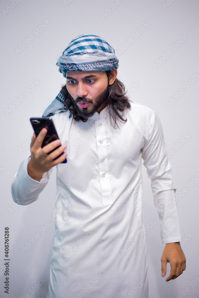 Religious man watching social media in the smart phone isolated on a grey background Religious man watching social media in the smart phone isolated on a grey background