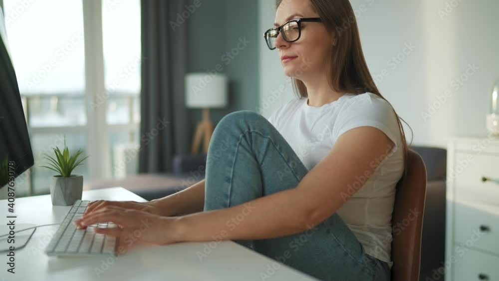 Casually dressed woman working with a computer at home in a cozy environment. Remote work outside the office. Casually dressed woman working with a computer at home in a cozy environment. Remote work outside the office.