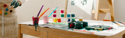 Slika na platnu Child painting her hand with paint and paintbrush