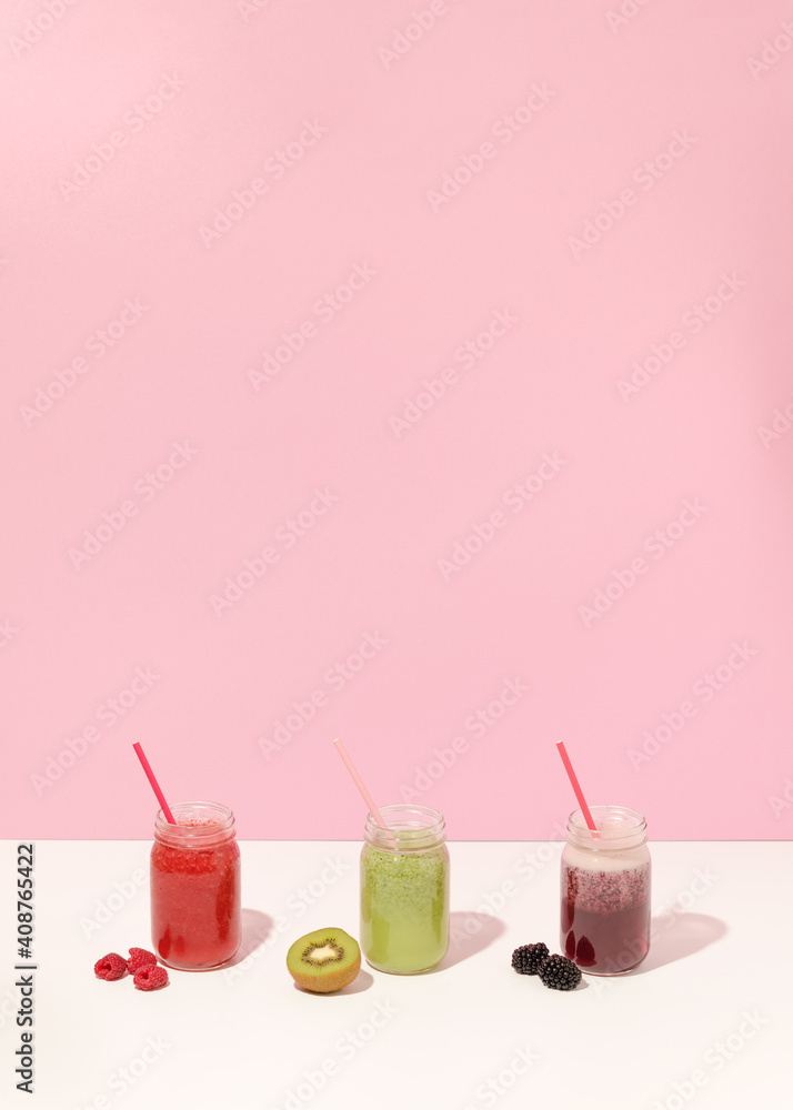 Summer colorful fruit smoothies in jars on pink background. Healthy, detox and diet food concept. Copy space