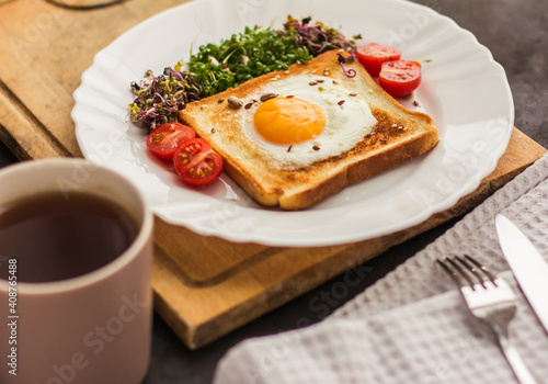 A sandwich with egg in the hole of the bread, microgreens, healthy food Breakfast, a cup of tea