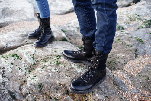 Girl and a guy are standing on the seashore in black boots