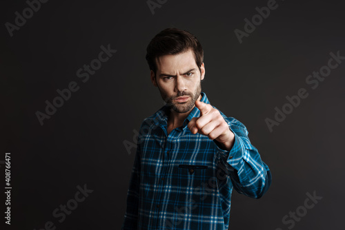 Displeased handsome brunette guy pointing finger at camera