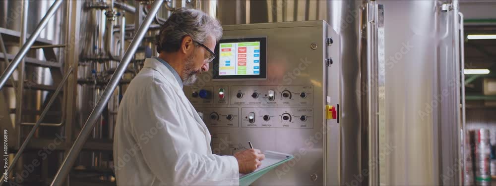Scientist in white lab coat taking notes from machine monitor. Factory concept. Scientist in white lab coat taking notes from machine monitor. Factory concept.