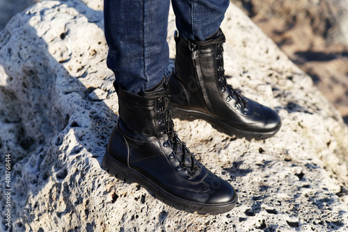 Black and lace-up outdoor shoes against the backdrop of rock and sand nature