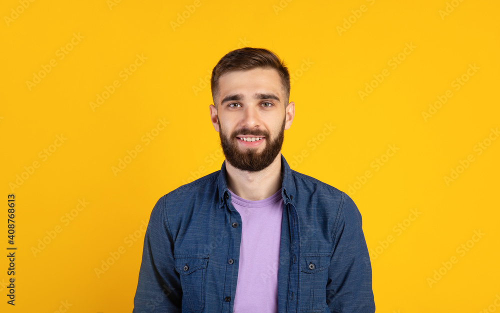 Carefree young guy looking at camera and smiling over orange studio background, panorama Carefree young guy looking at camera and smiling over orange studio background, panorama