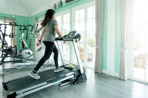 Woman walking exercise on a treadmill at home © iSomboon
