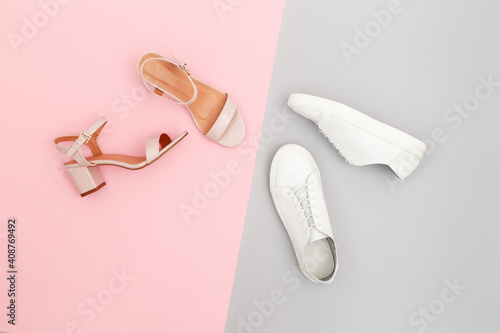 White sneakers and pink heeled sandals on grey and pink paper background. Stylish spring or summer woman's shoes in pastel colors. Trendy beauty female fashion background. Flat lay, top view.