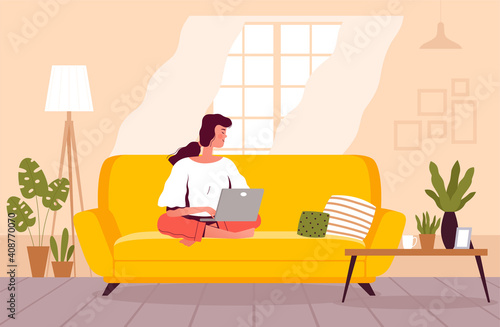 A freelancer woman is sitting on the couch and working on a laptop. The girl studies at home. Home office concept