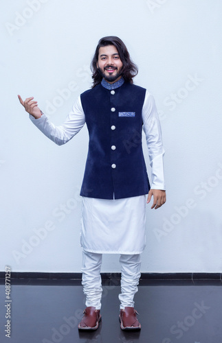 Pakistani Man Pointing with both hands fingers at right side with corse legs on white background at studio. photo