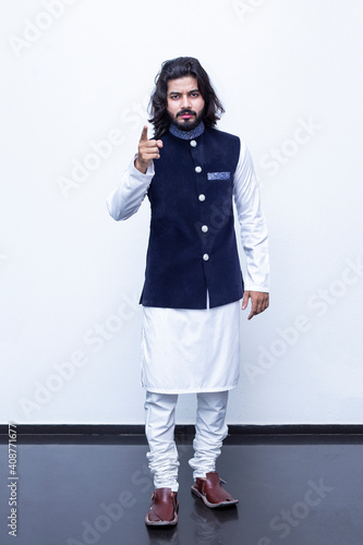 Pakistani Man Pointing with both hands fingers at right side with corse legs on white background at studio.