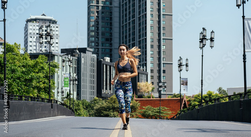 Woman running on city road with buildings in background