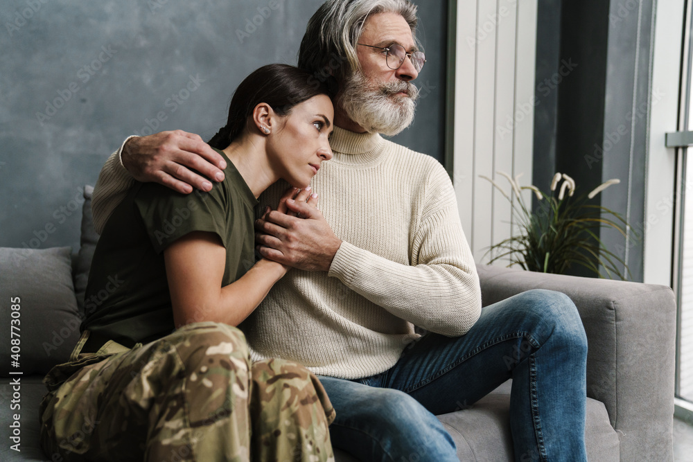 Serious mature father hugging and holding his military daughter's hand Serious mature father hugging and holding his military daughter's hand