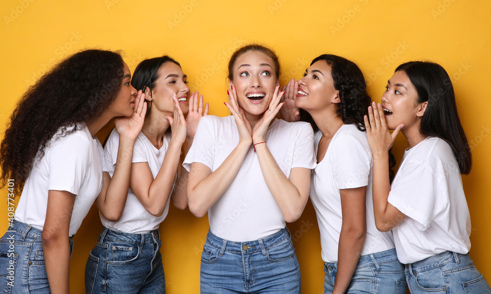 Fototapeta premium Excited Young Women Gossiping Sharing Rumors And Secrets, Yellow Background