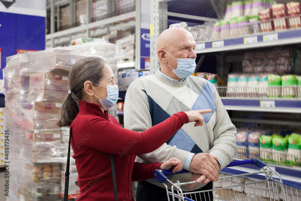 Elderly couple shopping in a supermarket and wearing medical face masks