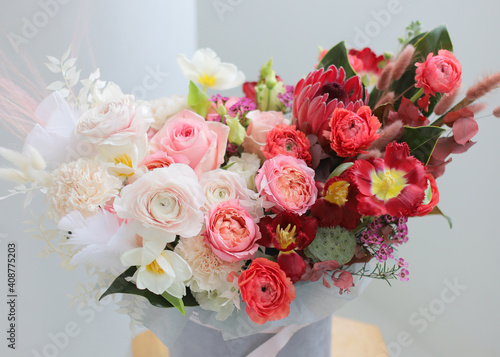 Floral bunch in round grey box. Fresh delicate bouquet of beautiful Mixed flowers in light room. Excellent garden flowers in the arrangement   the work of a professional florist. Gift box. 