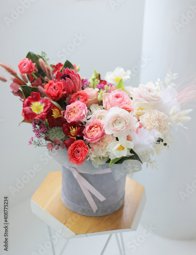 Floral bunch in round grey box. Fresh delicate bouquet of beautiful Mixed flowers in light room. Excellent garden flowers in the arrangement   the work of a professional florist. Gift box. 